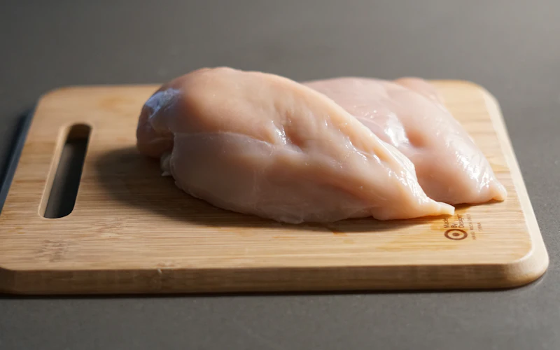 Raw chicken breasts on a wooden board